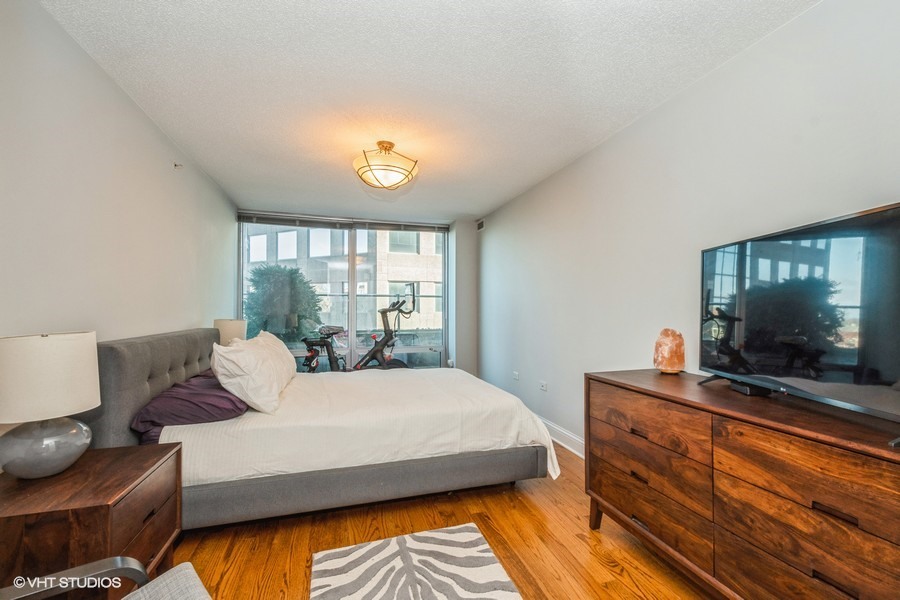 800 Elgin Road, Unit 517 Evanston, IL 60201 - Photo 11 of 20 a bedroom with a bed and a flat tv screen on dresser