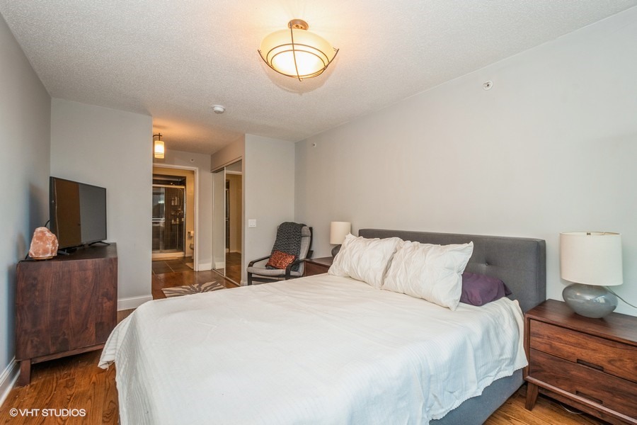 800 Elgin Road, Unit 517 Evanston, IL 60201 - Photo 12 of 20 a bedroom with a bed and a flat tv screen on dresser
