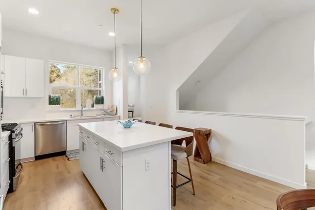 a view of a hallway with wooden floor and a bathroom