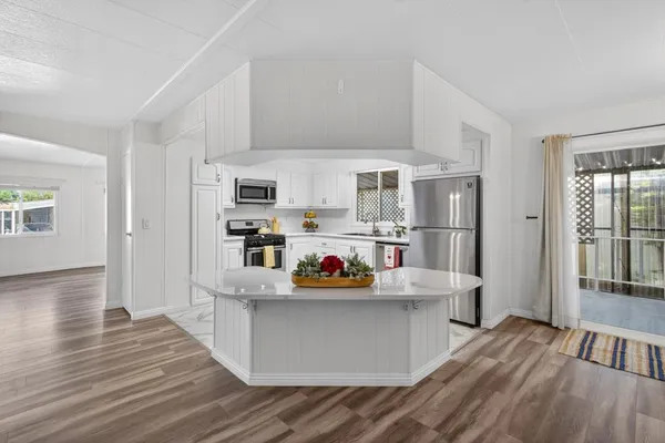 a kitchen view with wooden floor and stainless steel appliances