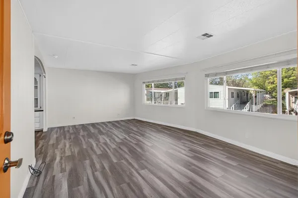 a view of empty room with wooden floor and fan