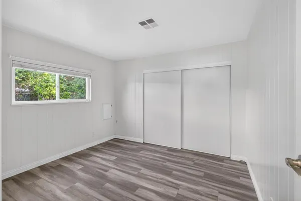 a view of an empty room with wooden floor and closet
