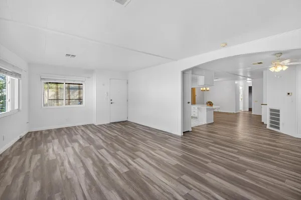 a view of a room with wooden floor and a kitchen