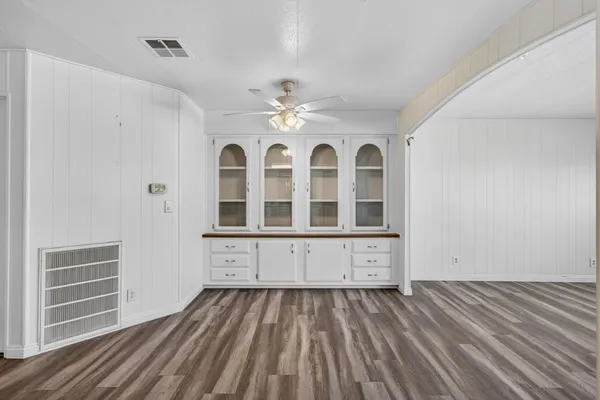 a view of a ceiling fan wooden floor and window