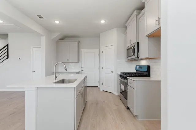 a kitchen with stainless steel appliances granite countertop a sink stove and cabinets