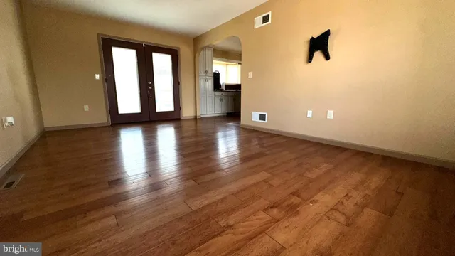 an empty room with wooden floor and windows