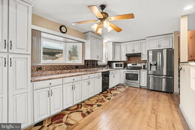 a kitchen with granite countertop stainless steel appliances a sink and a refrigerator