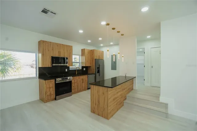 a large kitchen with stainless steel appliances granite countertop a large counter top and a stove top oven