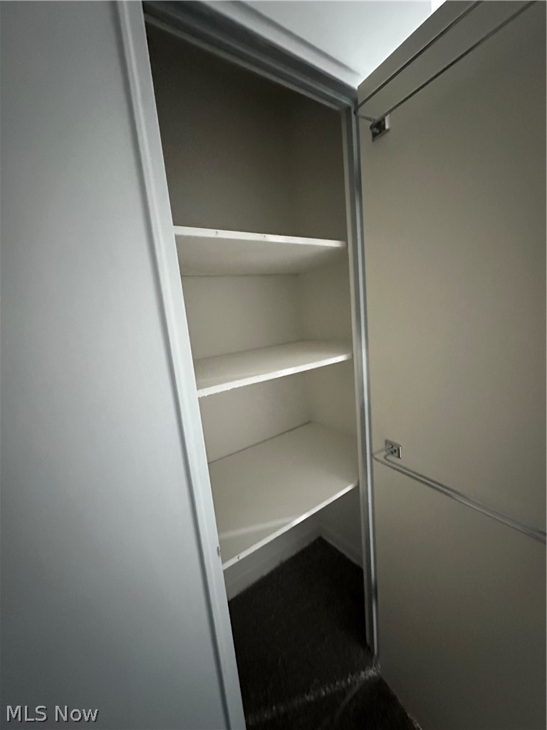 13800 Fairhill Road, Unit 416 Shaker Heights, OH 44120 - Photo 12 of 13 Built-in closet with white shelving, offering multiple storage tiers and a textured dark floor