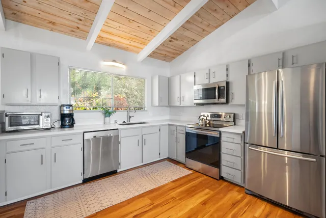 a kitchen with granite countertop stainless steel appliances a sink cabinets and a window