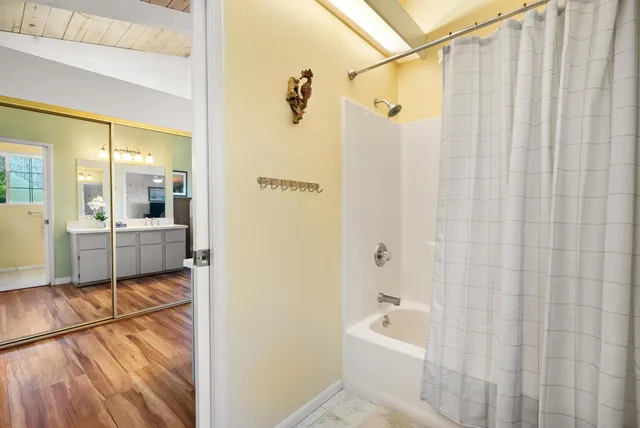 a bathroom with a sink a mirror a bathtub and shower