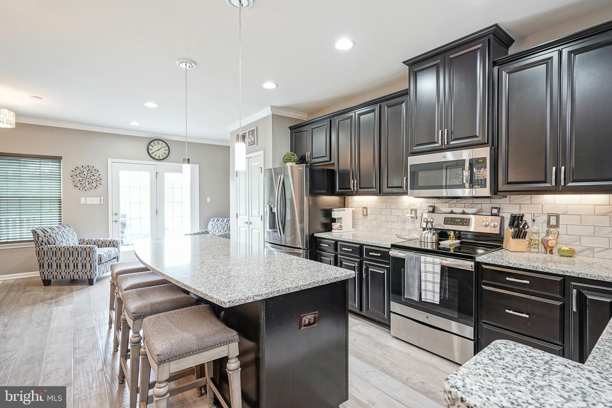 1056 Prime Place Sewell, NJ 08080 - Photo 11 of 41 a kitchen with stainless steel appliances granite countertop a stove a refrigerator a sink a dining table and chairs