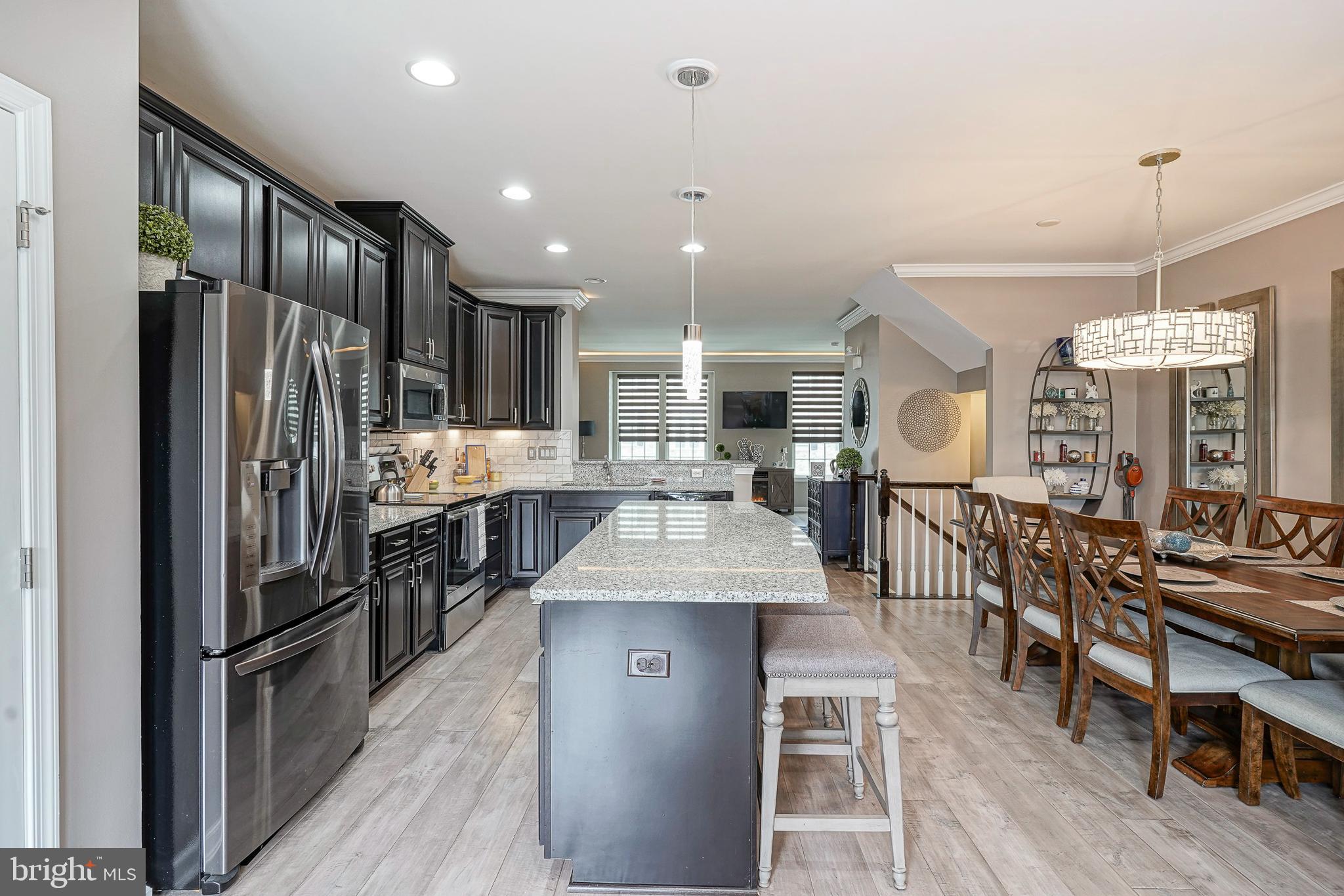 1056 Prime Place Sewell, NJ 08080 - Photo 20 of 41 a kitchen with stainless steel appliances granite countertop a refrigerator oven a sink dishwasher and a dining table with wooden floor