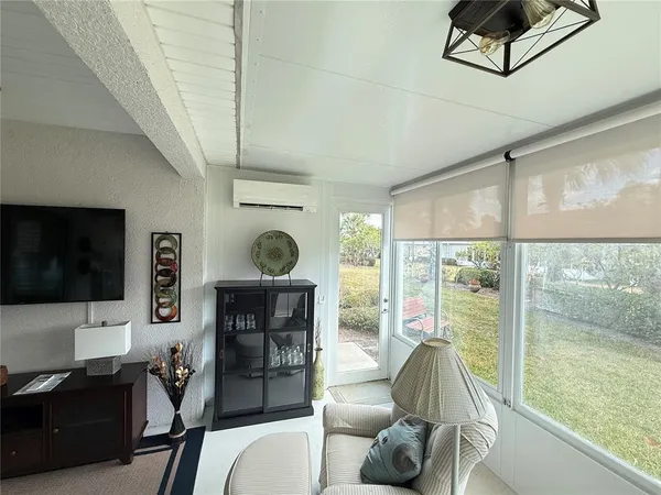 a living room with furniture a flat screen tv and a floor to ceiling window