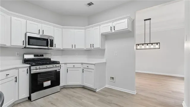 a kitchen with cabinets stainless steel appliances and wooden floor