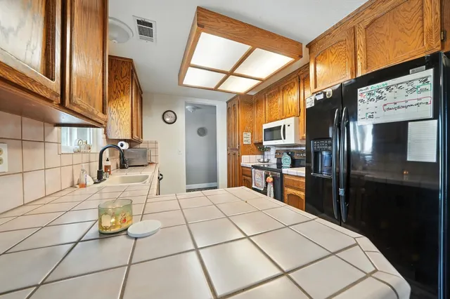 a kitchen with stainless steel appliances kitchen island granite countertop a refrigerator and a stove top oven