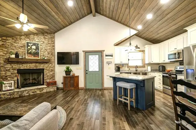 a living room with stainless steel appliances granite countertop furniture wooden floor and a kitchen view