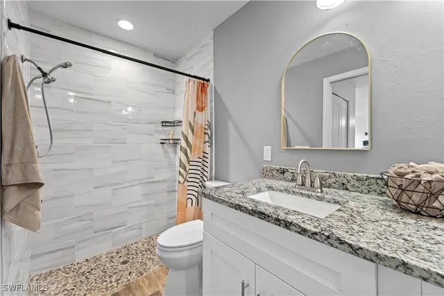 a bathroom with a granite countertop sink toilet and shower