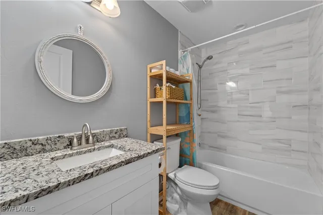 a bathroom with a granite countertop sink toilet and a mirror