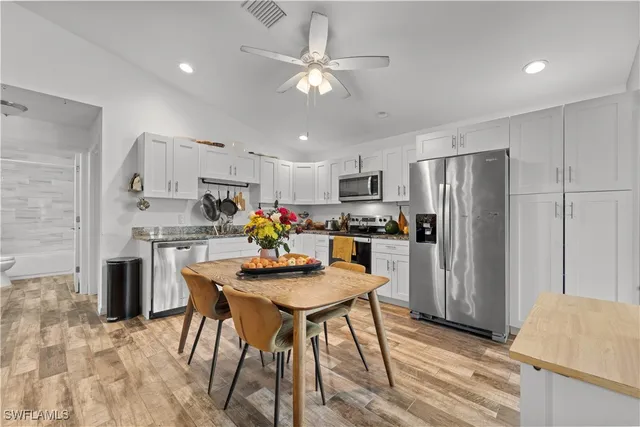 a kitchen with stainless steel appliances a dining table chairs refrigerator and microwave