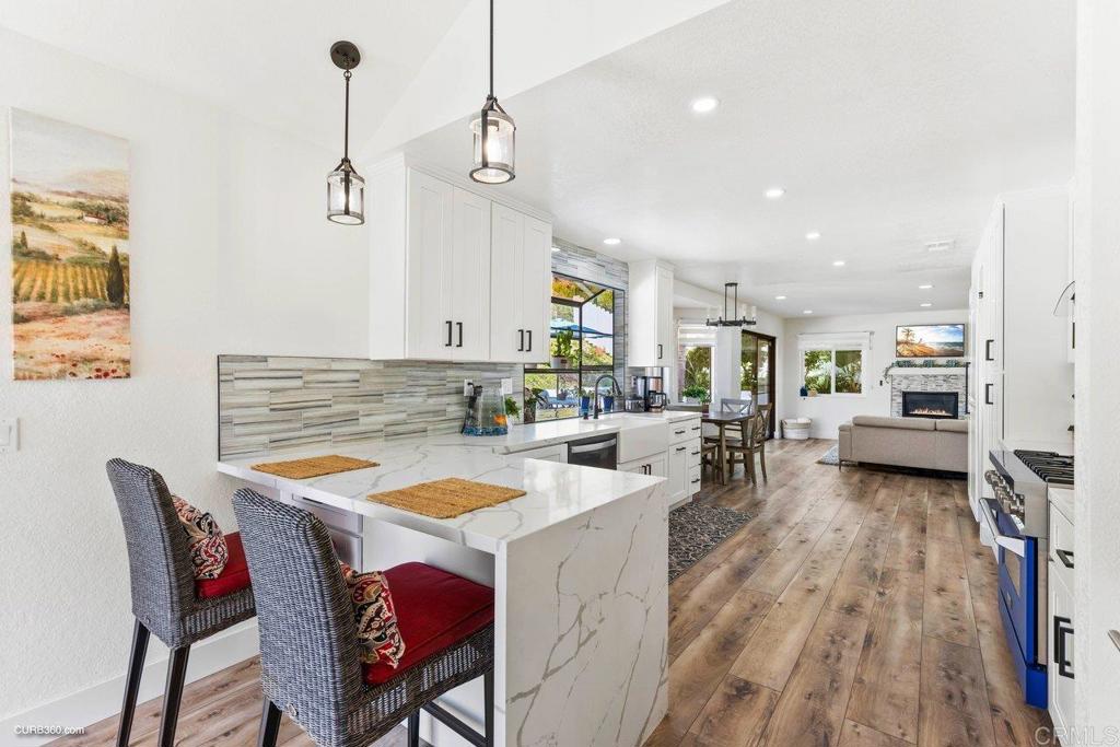 1618 Buttercup Road Encinitas, CA 92024 - Photo 15 of 33 a view of a dining room and livingroom with furniture wooden floor a rug a flat screen tv a painting and a chandelier