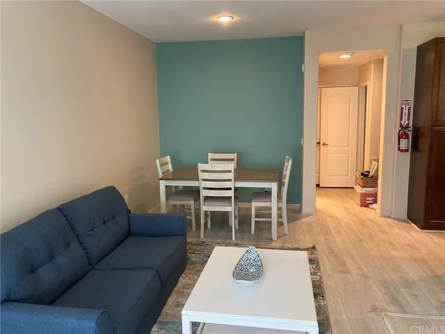 a living room with furniture a flat screen tv and a refrigerator