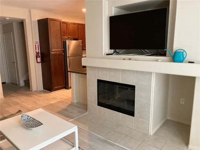 a living room with stainless steel appliances furniture a fireplace and a flat screen tv
