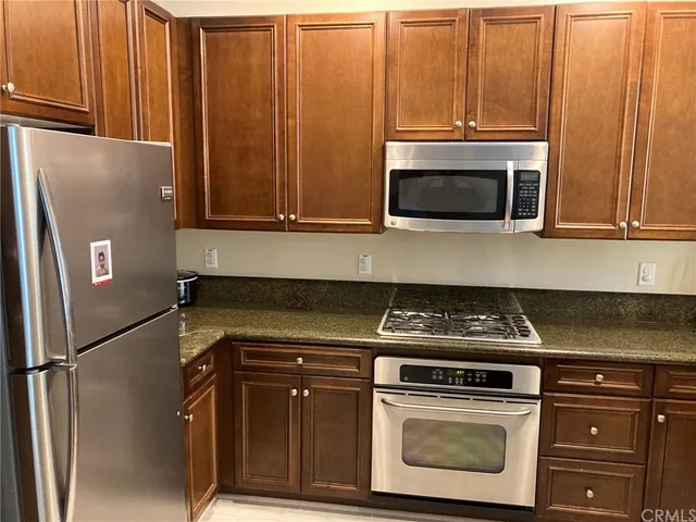 a kitchen with granite countertop cabinets stainless steel appliances and a refrigerator