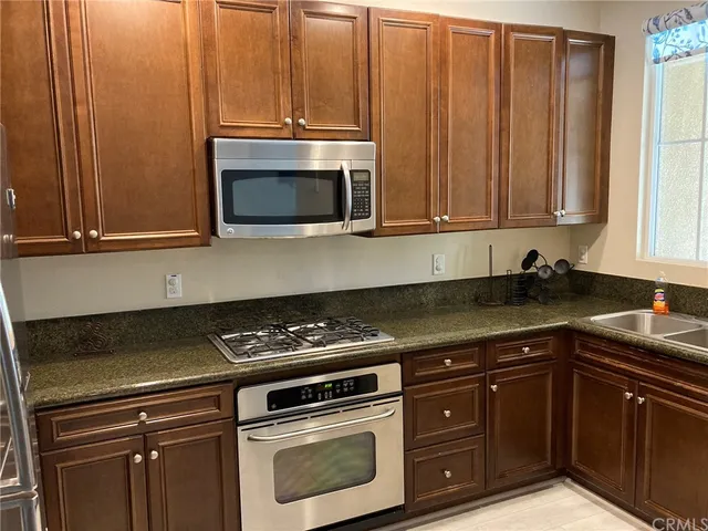 a kitchen with granite countertop wood cabinets and stainless steel appliances