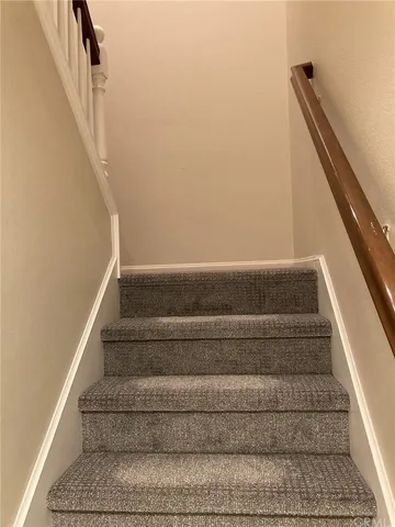 a view of staircase with white walls and a floor