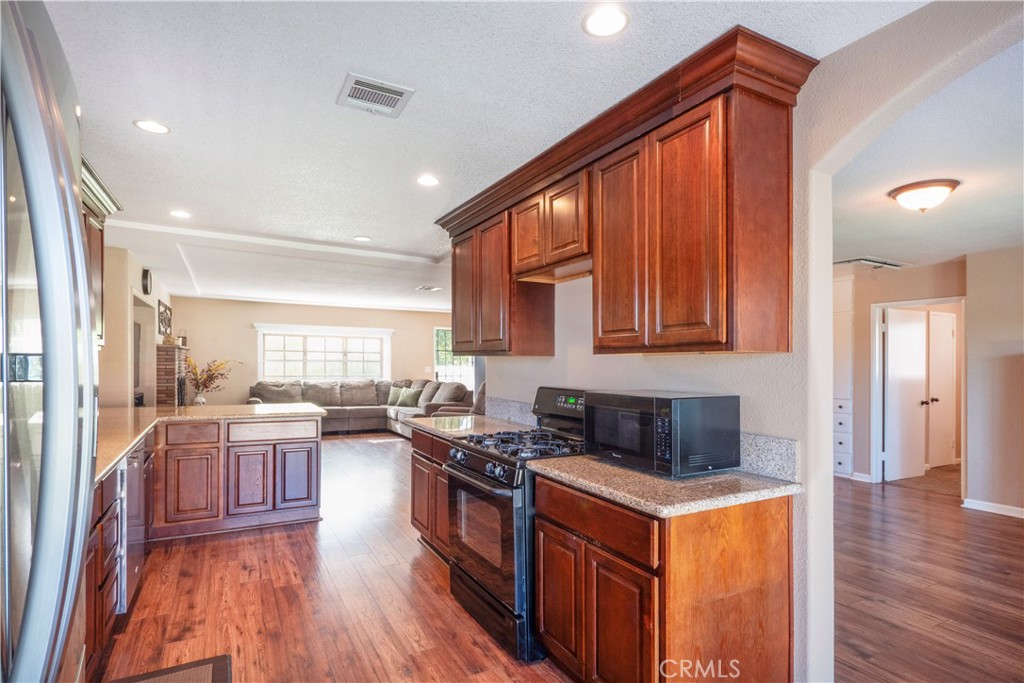 11665 Valverda Avenue Riverside, CA 92505 - Photo 18 of 53 a kitchen with stainless steel appliances granite countertop a stove and a wooden floors