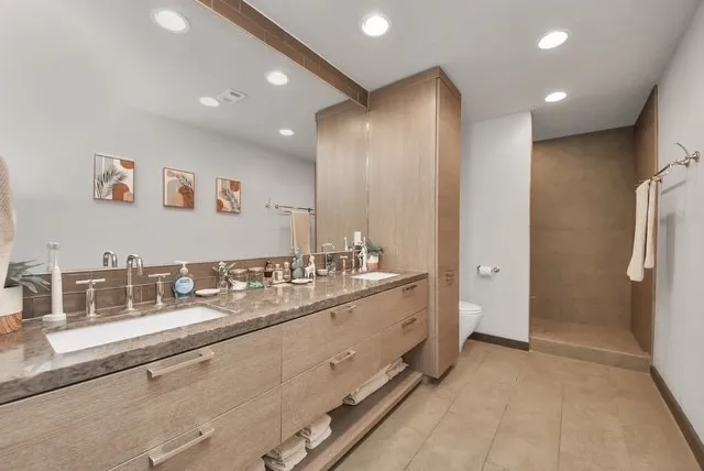 a spacious bathroom with a double vanity sink a mirror and a shower