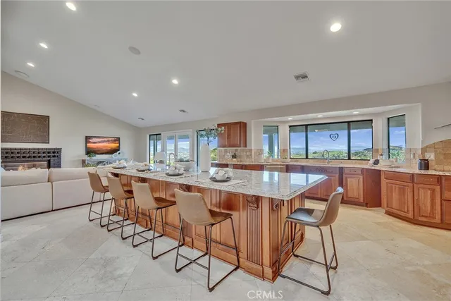 a large kitchen with granite countertop a large counter top cabinets and stainless steel appliances