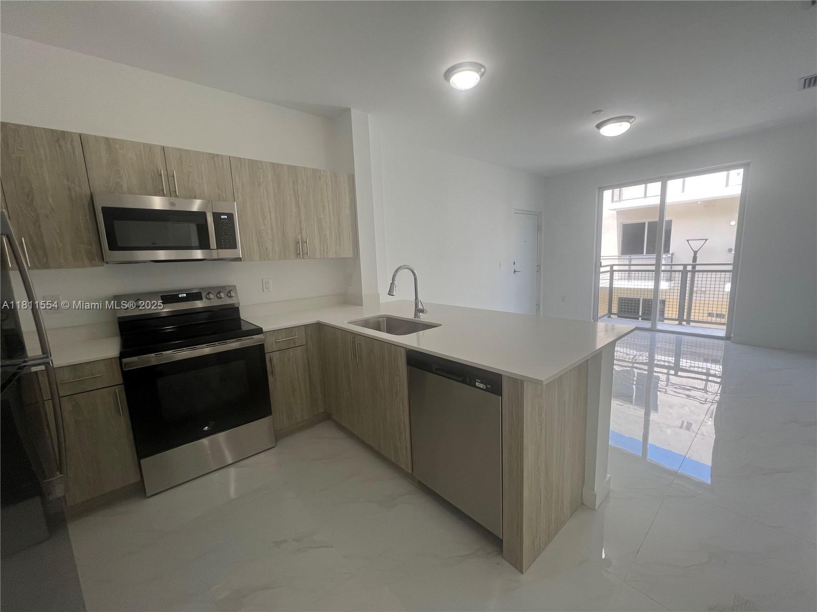 1010 Southwest 69th Avenue, Unit 212 Miami, FL 33144 - Photo 2 of 30 a kitchen with granite countertop a refrigerator and a stove top oven