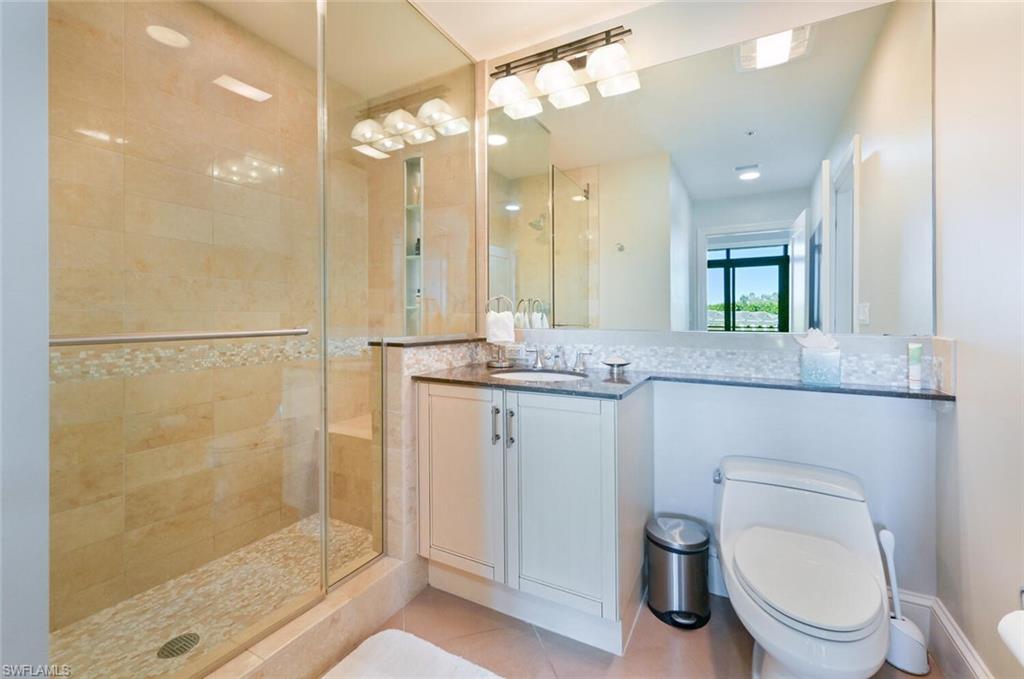 9115 Strada Place, Unit 5211 Naples, FL 34108 - Photo 11 of 31 a bathroom with a granite countertop sink a toilet a mirror and shower