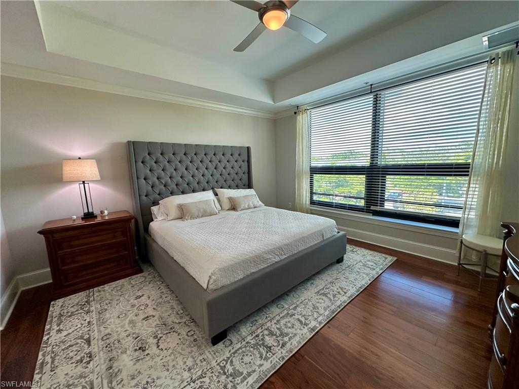 9115 Strada Place, Unit 5211 Naples, FL 34108 - Photo 5 of 31 a bedroom with a large bed and a lamp on dresser with wooden floor