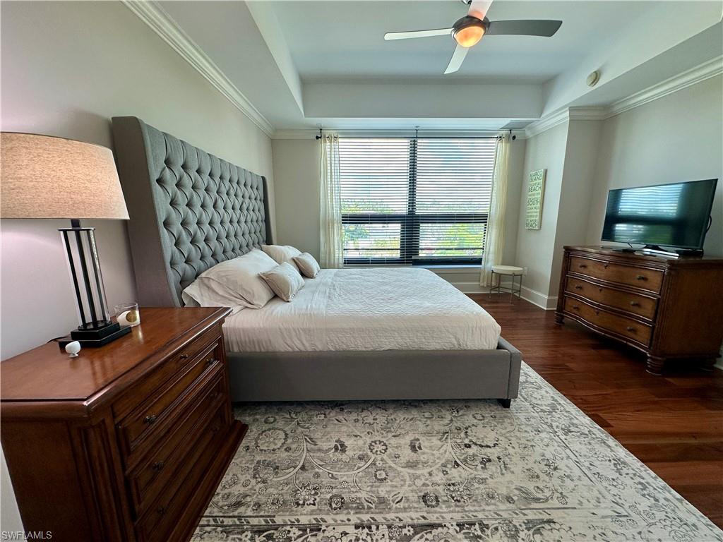 9115 Strada Place, Unit 5211 Naples, FL 34108 - Photo 6 of 31 a bedroom with a bed wooden floor and a flat screen tv