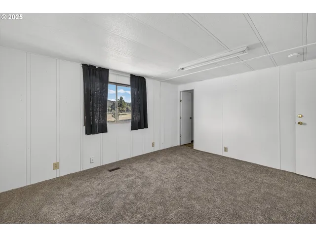 a view of an empty room with window and stairs