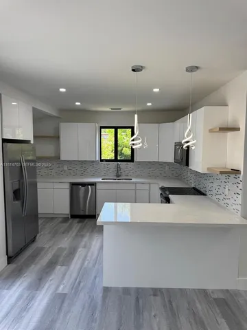 a large kitchen with a large counter top a sink stainless steel appliances and cabinets