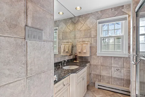 a bathroom with a granite countertop sink a mirror and a shower