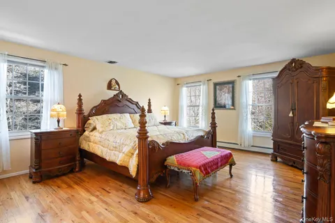 a spacious bedroom with a bed a dresser and wooden floor