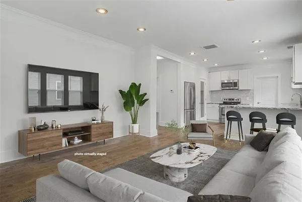 a living room with furniture kitchen view and a wooden floor