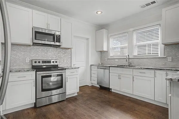 a kitchen with granite countertop a stove a sink and a microwave