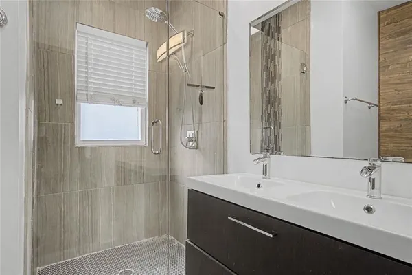 a bathroom with a double vanity sink a shower and a mirror