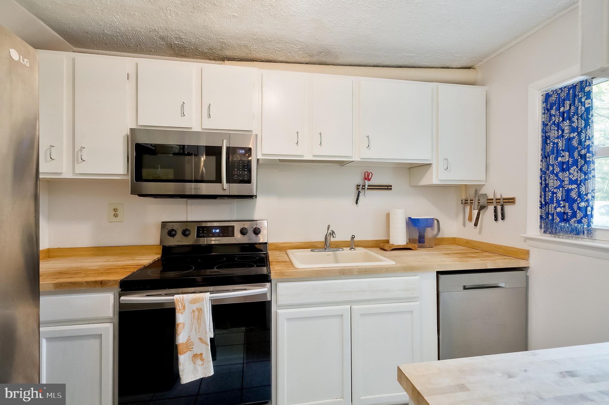 71 Ridge Road Greenbelt, MD 20770 - Photo 10 of 24 a kitchen with granite countertop white cabinets and black appliances