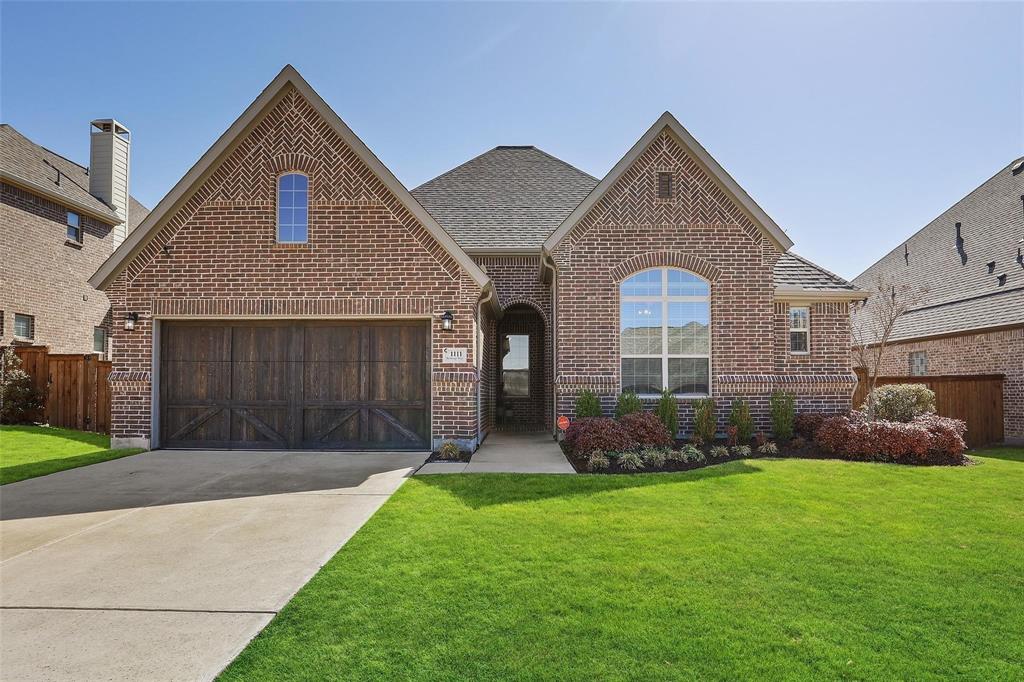 View of front of home with brick siding, a garage, driveway, and a shingled roof