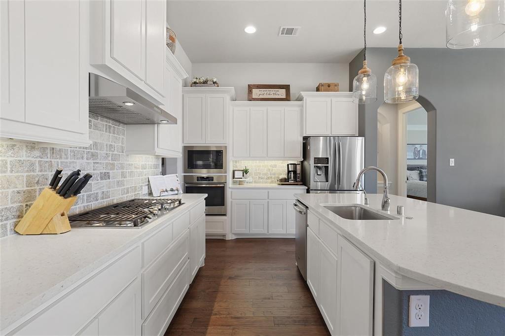 1111 Belknap Way Prosper, TX 75078 - Photo 7 of 24 Kitchen featuring white cabinetry, light stone counters, appliances with stainless steel finishes, pendant lighting, and recessed lighting