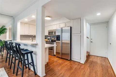 a view of kitchen with refrigerator stove and wooden floor