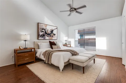 a spacious bedroom with a bed and wooden floor