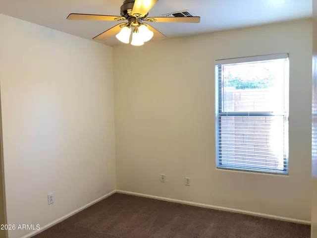 an empty room with a window and a fan